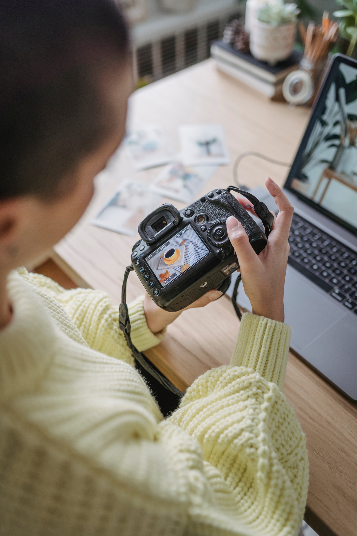 Unrecognizable photographer sitting at table while checking photo on camera